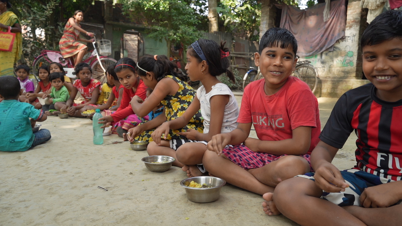 Village children sitting for Krishna prasadam